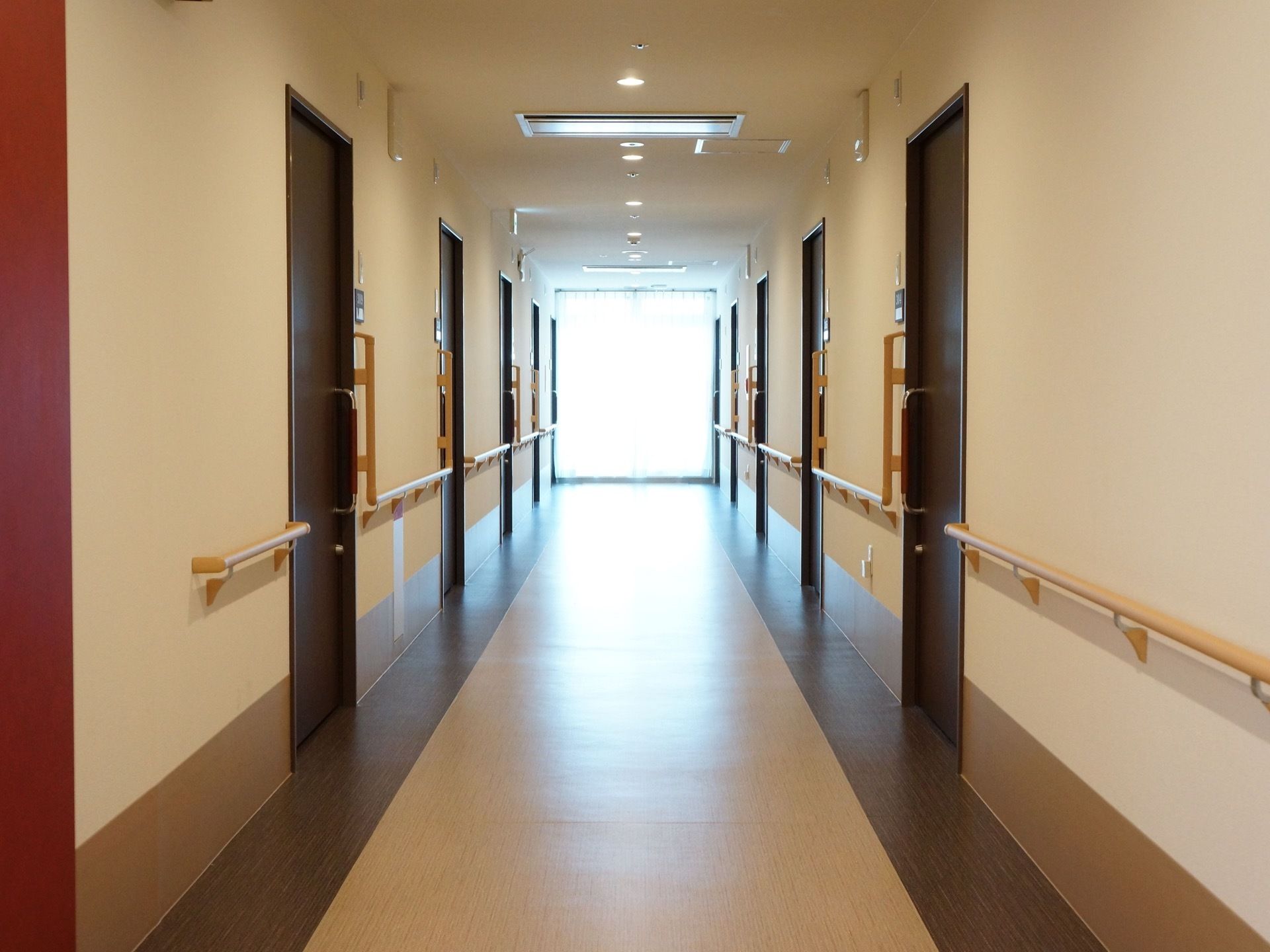 館内の通路の様子。左右の壁には手すりが取り付けられ、居室が並んでいる。各ドアは施錠可能なスライド式になっている。