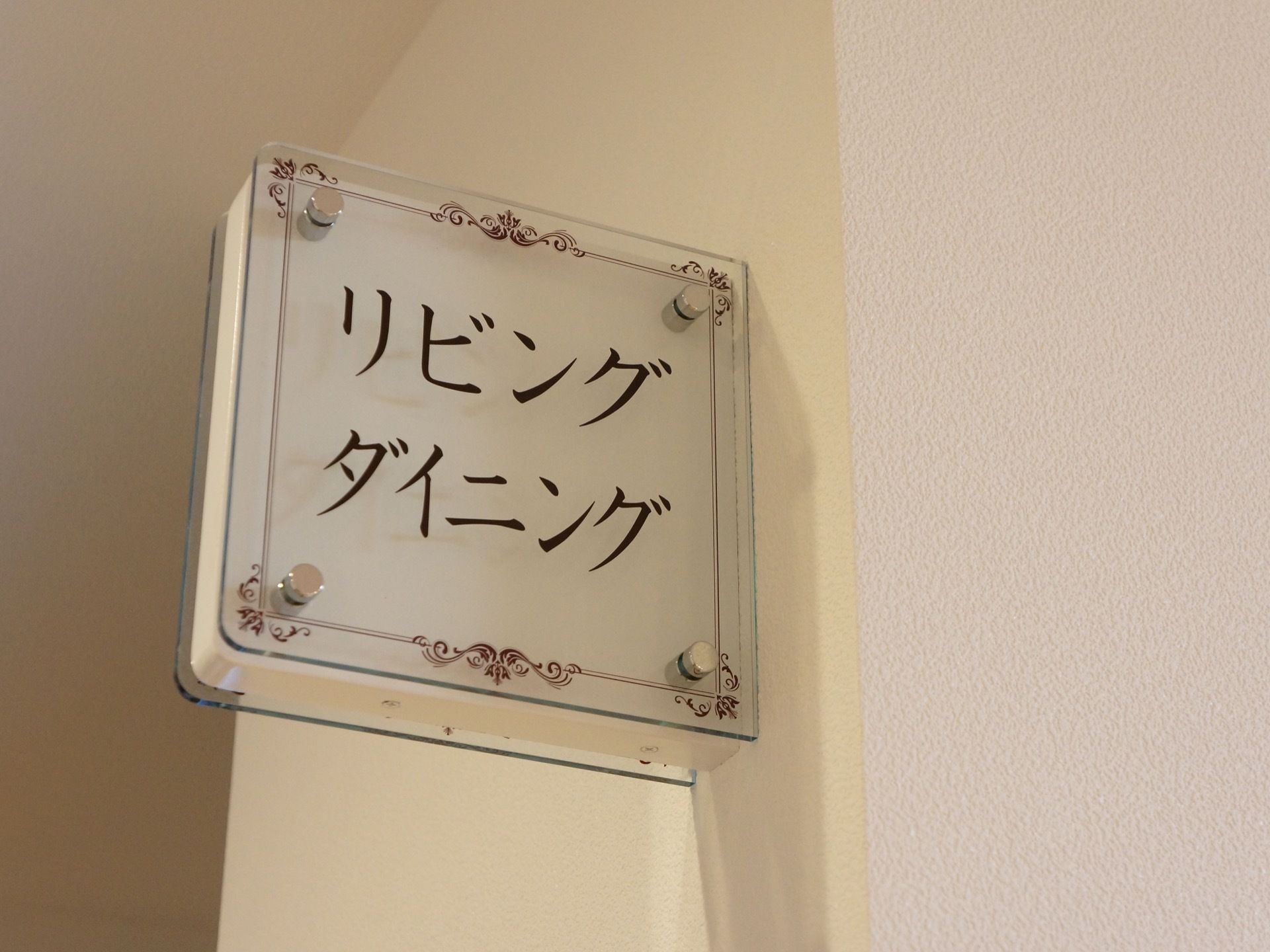 リビングダイニングと描かれた看板が部屋のドアの上に設置されている。透明な板に文字がプリントされている。