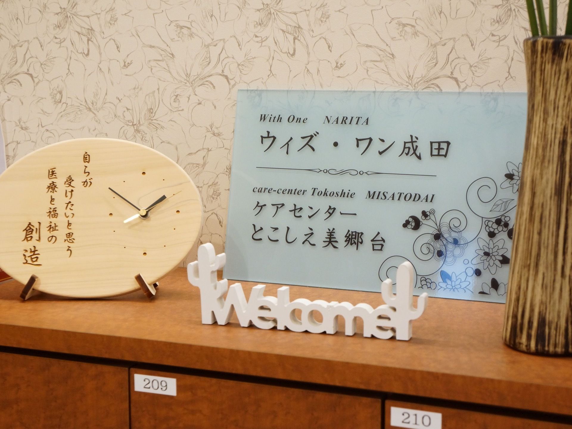 玄関の靴箱の上に飾られているインテリア類。ウェルカムボード代わりに施設名の看板プレートが置かれている。
