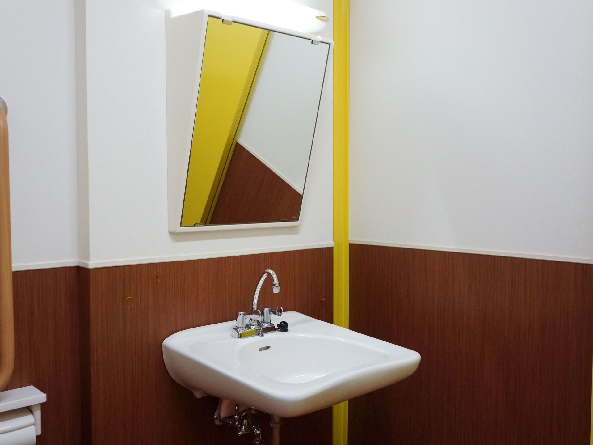 トイレの洗面台は、車椅子をご利用の方も使用しやすい配慮がされている。鏡は斜めに大きく取り付けられ、洗面台の足元はぶつかりにくい。