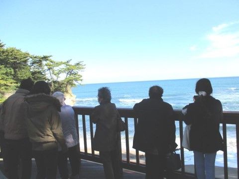 柵の前に立って、海や近くにある島を眺めている六人の人々