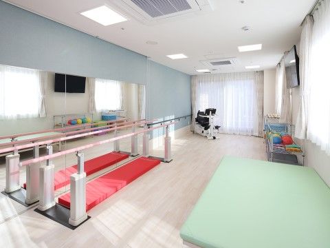 歩行部分に赤い長方形のマットが敷かれている、二台の歩行訓練機器