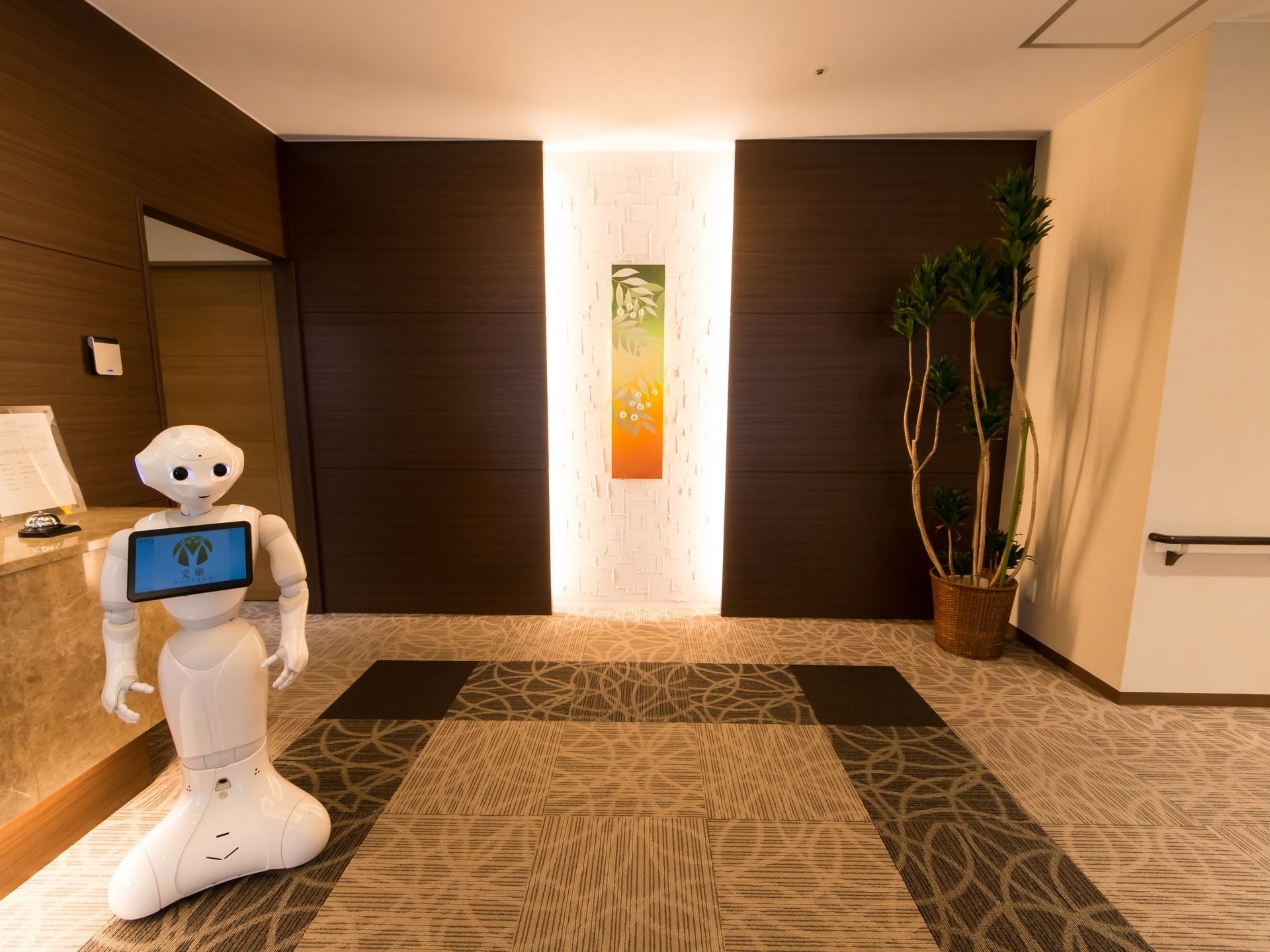 玄関ホールにはロボットのコンシェルジェが置かれている。正面の壁には、背景からライトで照らされたオブジェが飾られている。