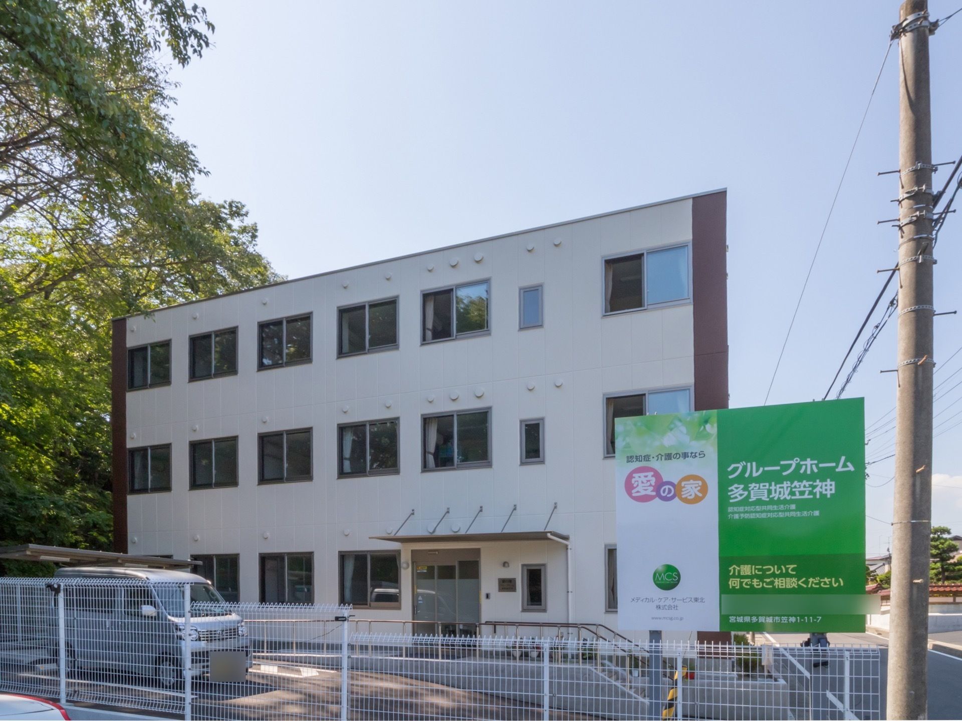 施設は３階建ての白い建物である。１階に入口があり、入口まではスロープが設置されている。建物前には駐車場がある。