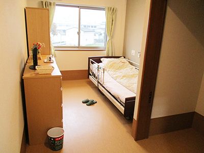 右側に柵付きのベッドがあり、左側にタンスとクローゼットが設置されている居室