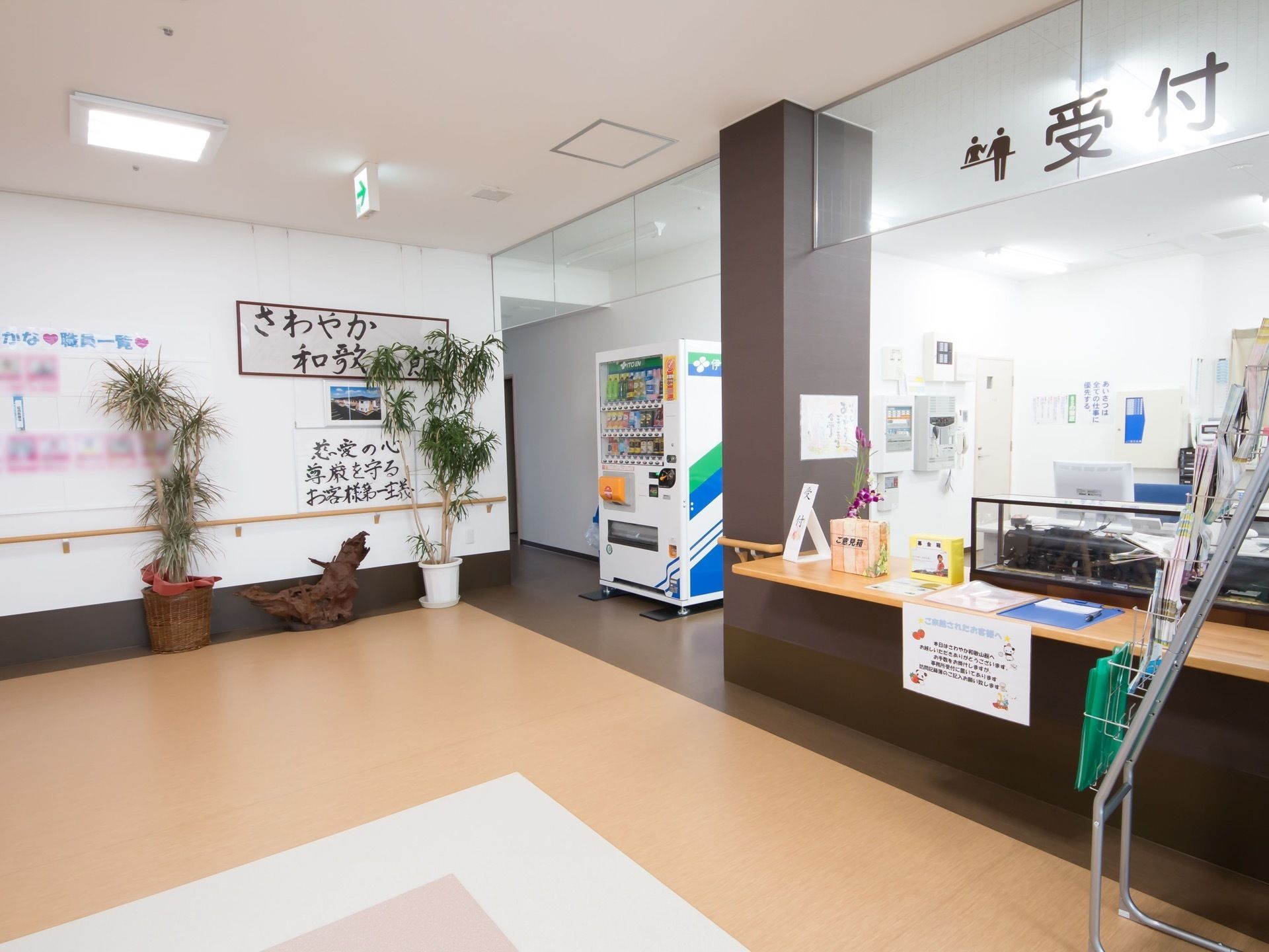 受付付近にはパンフレットが設置されている。自動販売機設けられている。観葉植物や壁には制作物が飾られている。