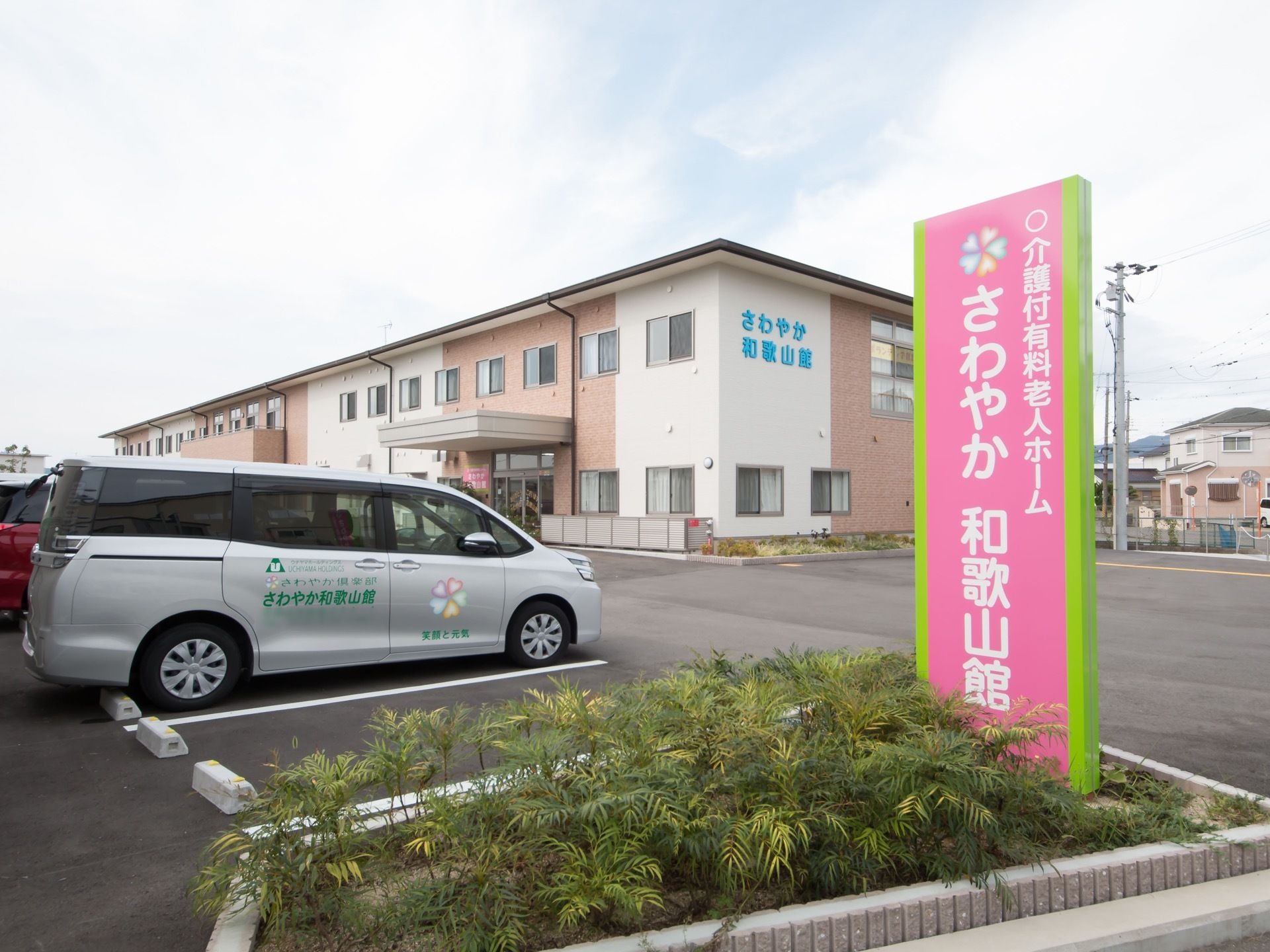2階建ての施設外観になっている。敷地内には、広い駐車スペースが設けられている。敷地の出入り口には、施設名が記された看板が設置されている。