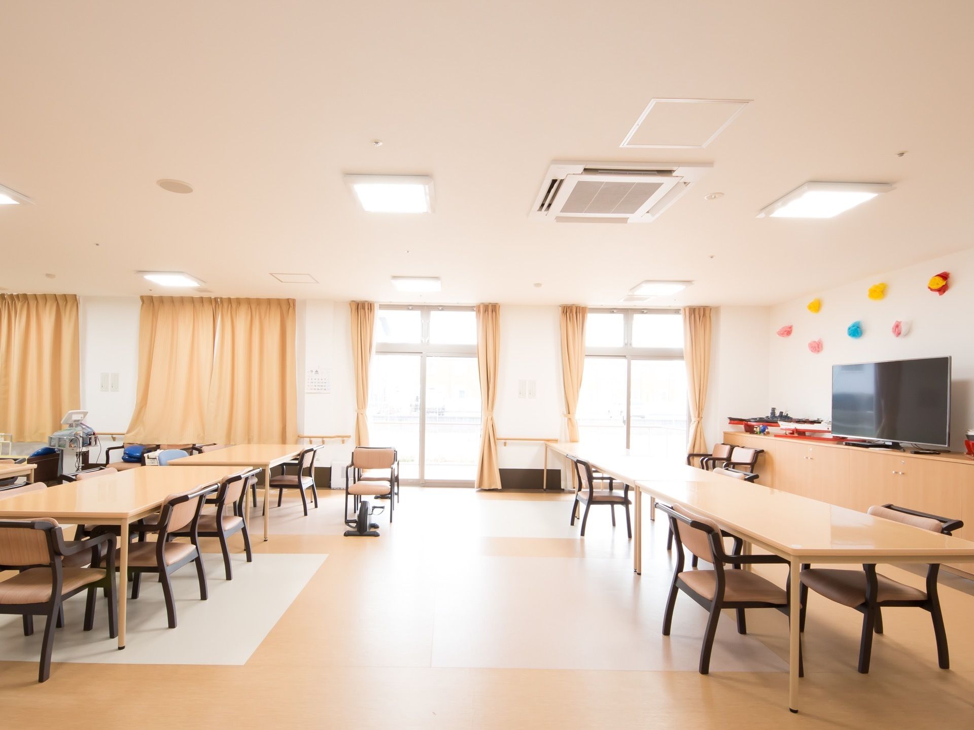 大きな窓からは光が差し込んで明るい。テーブルと椅子がいくつも並んでいる。棚にはテレビが置かれている。