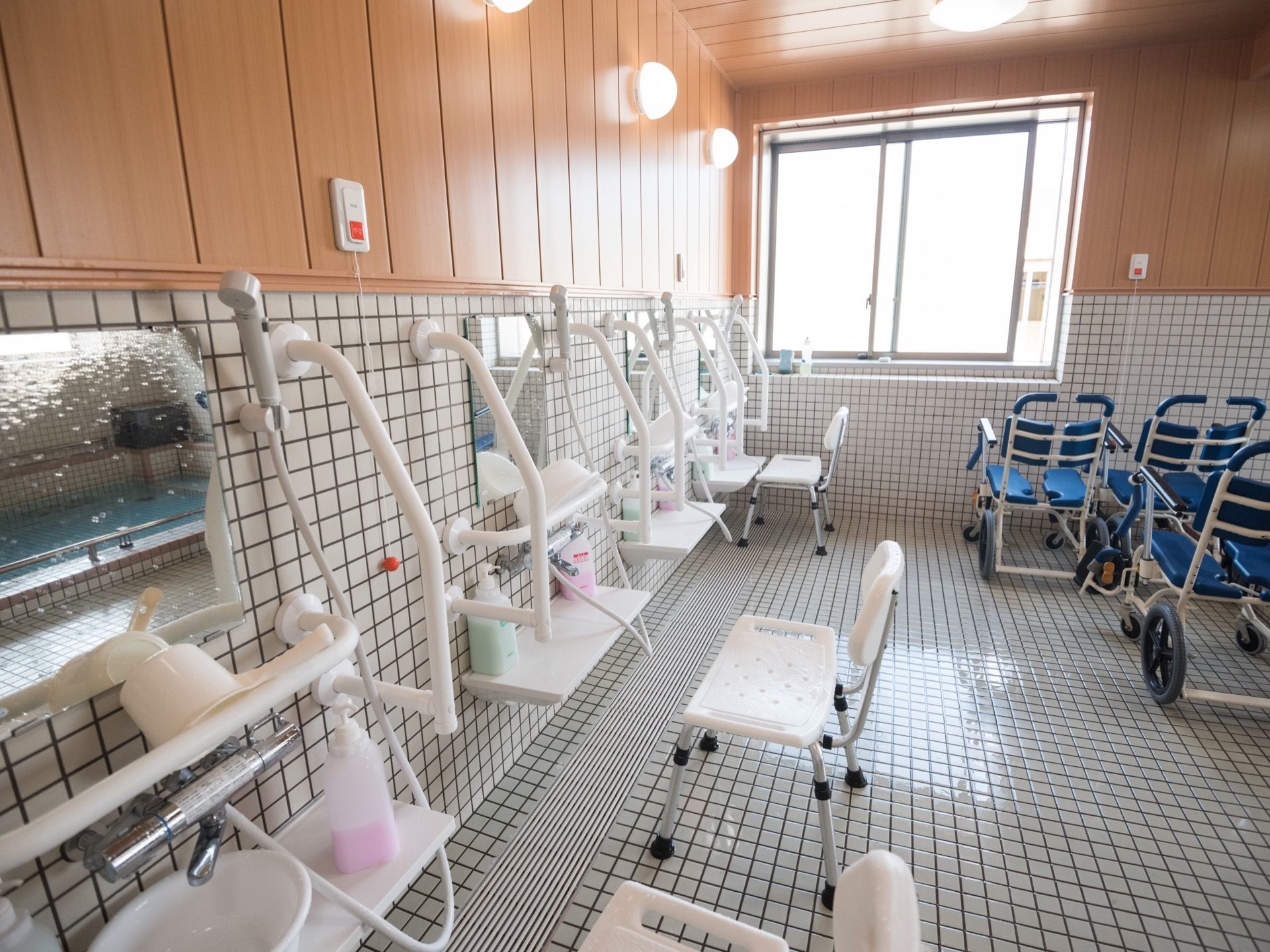 洗い場の壁には４人分のシャワーや鏡が取りつけられており、各台の上にはシャンプーなどが用意されている。