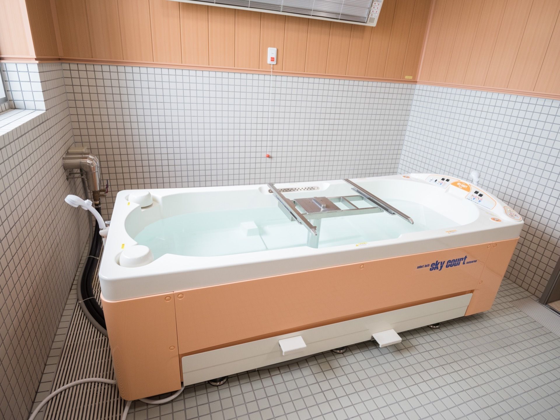 横になったままの姿勢で入浴ができる機械浴槽が置かれている。暖房の下には、ナースコールが設置されている。