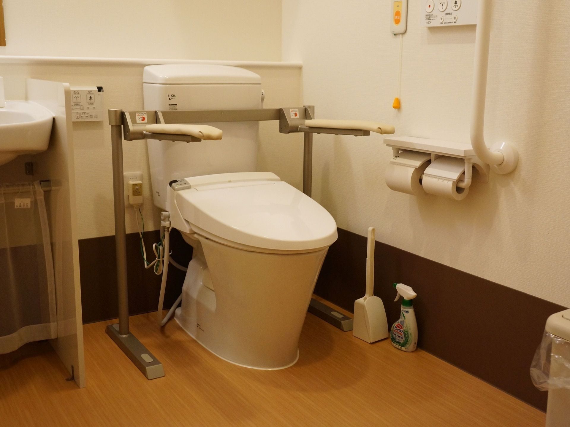 白色の清潔感あるトイレが設置されている。そばにブラシと洗剤があり、隅々まできれいに清掃されている。手すりもある。