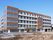 ５階建てのマンション風の建物。白と赤茶色の外壁が明るい雰囲気を感じさせる。１階部分には保育所が併設されている。