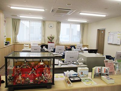 木目調とベージュの内装が優しい雰囲気の事務所。モスグリーンのカーテンや部屋の奥の花瓶など、目に優しい空間になっている。
