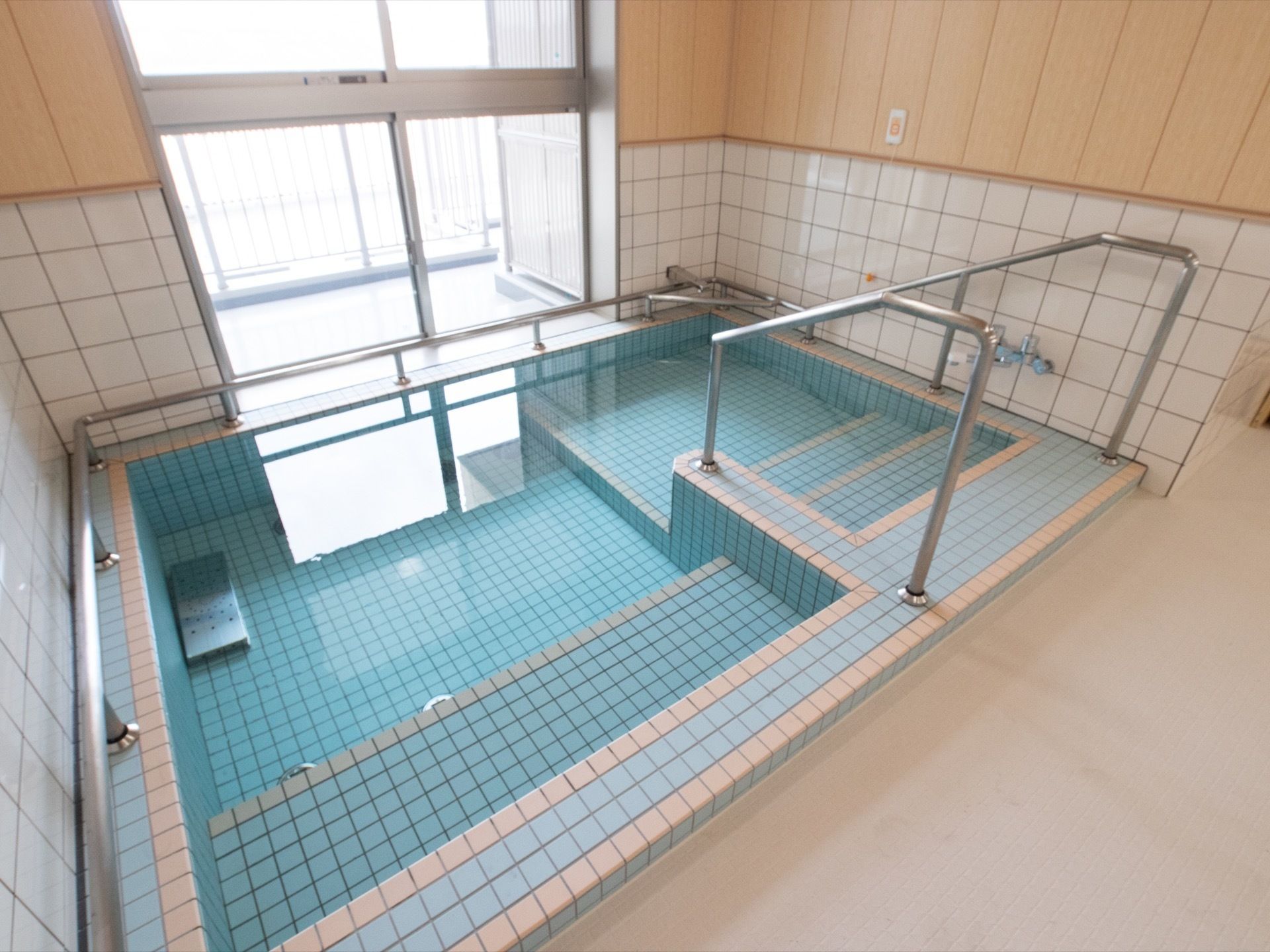 大浴場の浴槽の周りには、銀色の手すりが付いている。また浴槽に入る階段の両側にも手すりがあり、安定感を保って入浴できる。