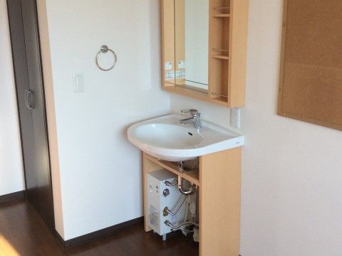 洗面台の足回りと上部の棚には、木材を利用している。レバー式の蛇口は、左右上下に動かして水の調節をする。
