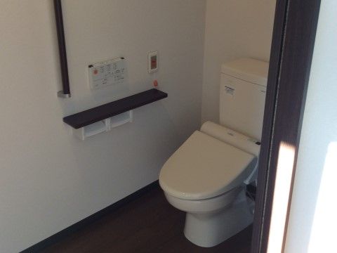トイレのペーパーホルダーの上は、黒い小棚になっている。個室内には、緊急時に外へ知らせる呼出ボタンがついている。