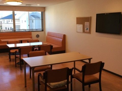 リビングには一人掛けの椅子や複数人で座れるソファーがあり、ゆっくりとくつろげる空間になっている。窓からは近くの民家が見える。