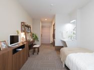 居室にはローチェストがあり、液晶テレビが置かれている。また室内にはベッドがあり、洗面台を設置している。