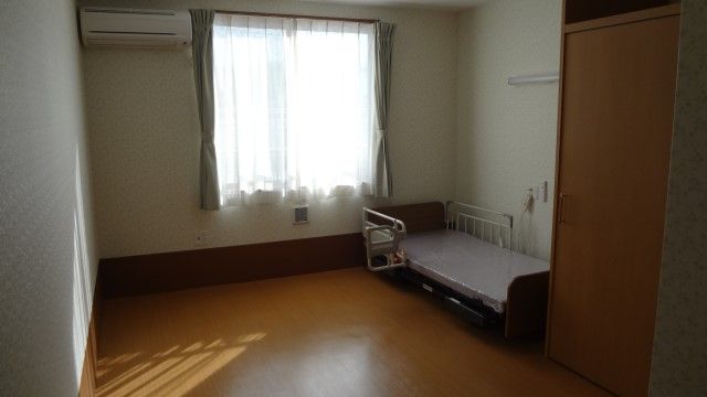 木目調のフローリングに設置されている、マットなどが置かれていない柵付きベッド