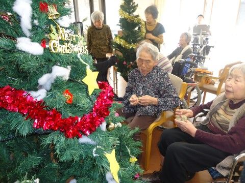 入居者様がクリスマスツリーの飾り付けをしている。入居者様で飾り付けを楽しみ、クリスマスならではの食事が用意される。