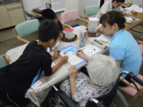 男の子と一緒に塗り絵をしている、車椅子に座った入居者の女性