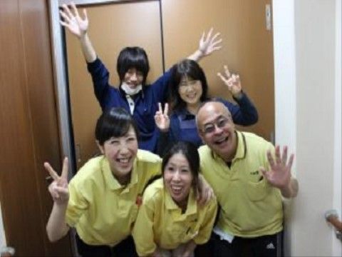 木製のドアの前に集まり、ポーズをとっている笑顔のスタッフたち