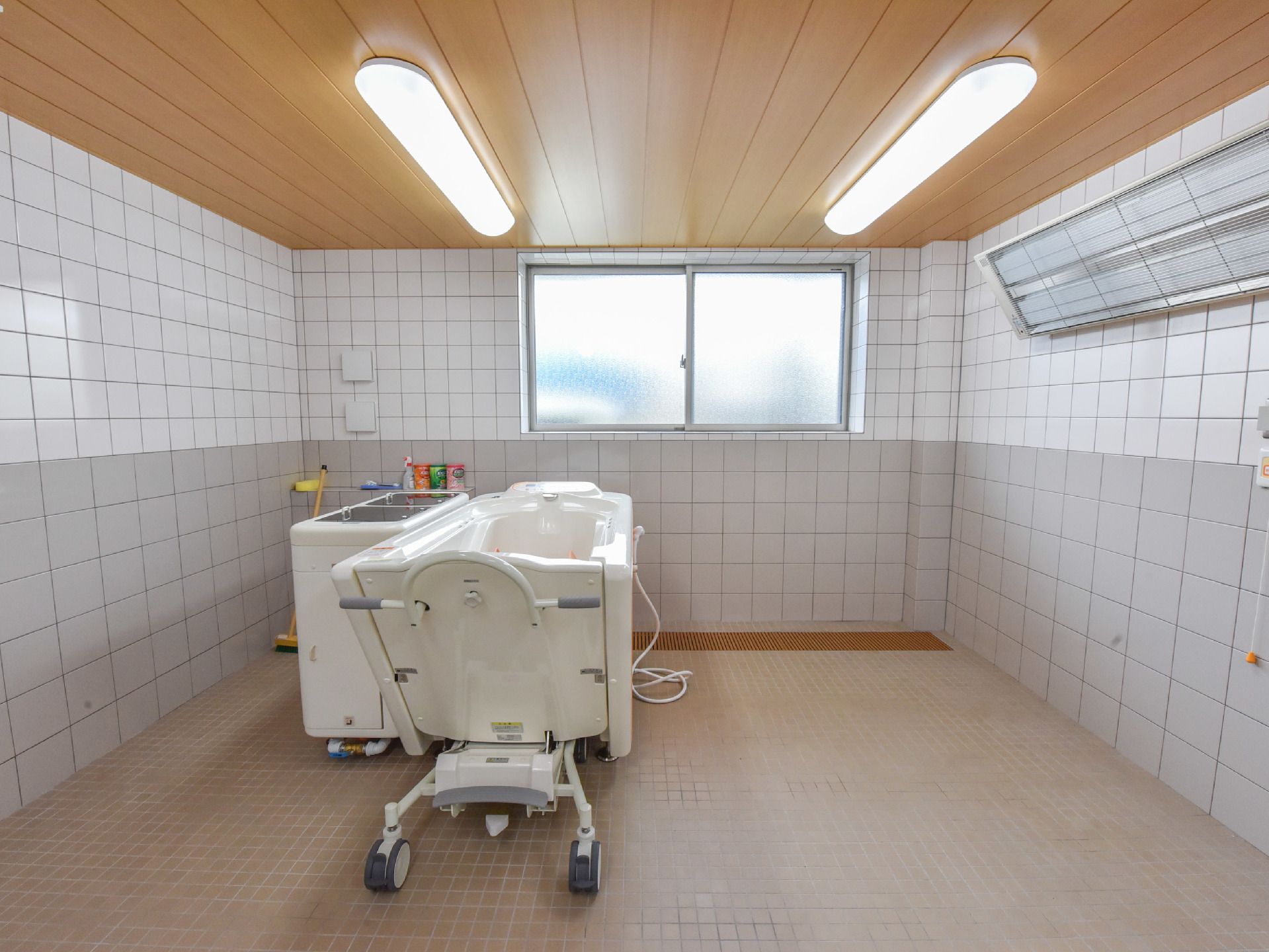 当施設の浴室を撮影した画像である。画像に写っている浴槽は介護浴槽で、座ったまま入浴ができるという機能がある。