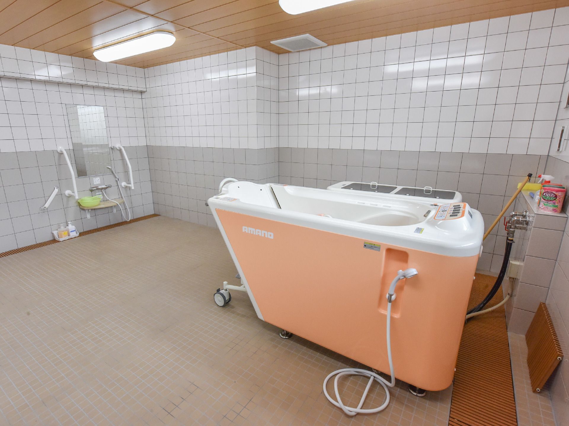 当施設の浴室を写した画像である。壁と床は一面タイル貼りになっている。床は一色だが、壁には白と灰色のタイルが使われている。