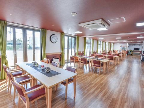 揃いのテーブルセットが窓際に規則正しく並べられているダイニング