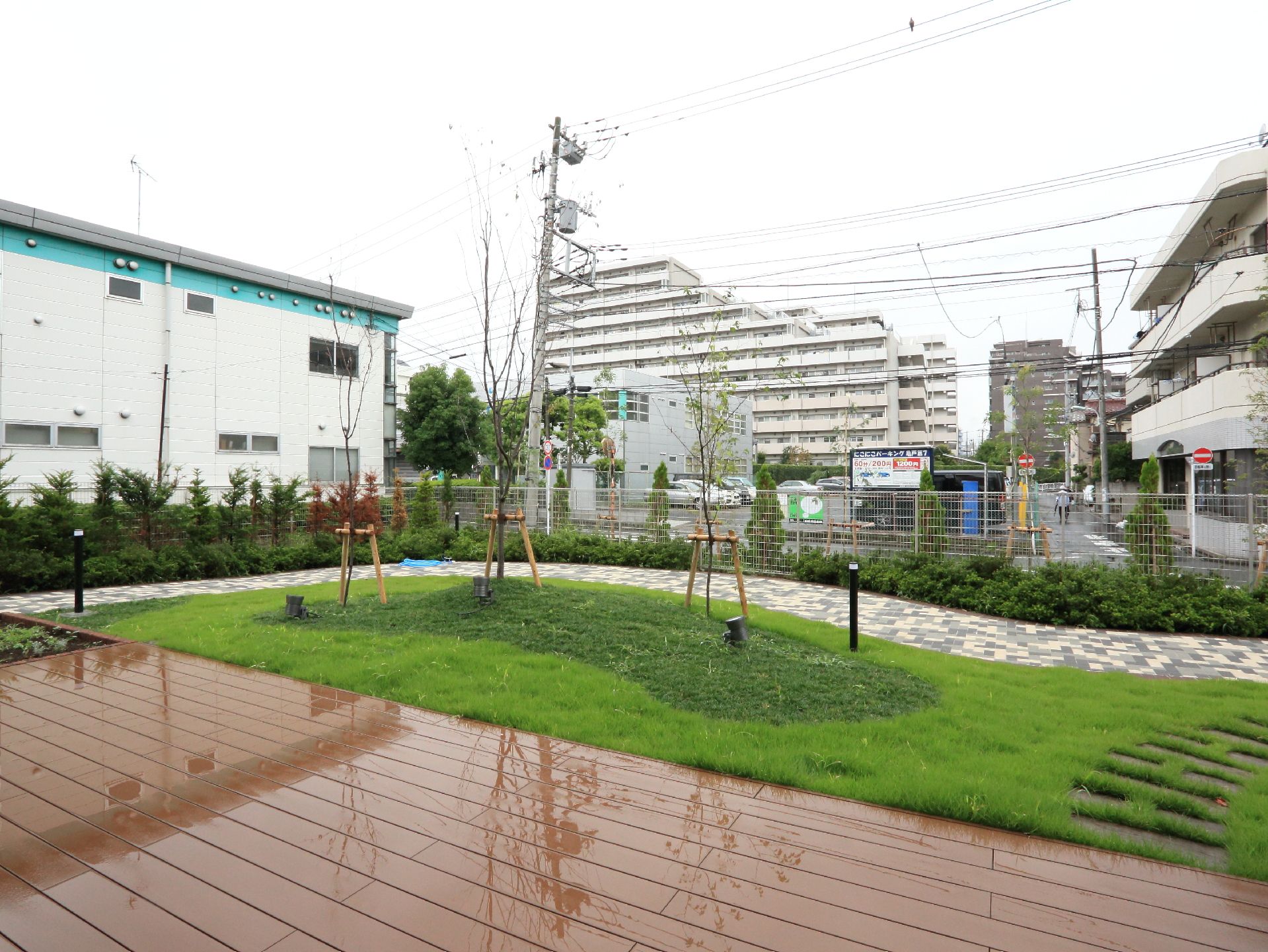 施設の庭は、レンガ色の石造テラスに続いて緑の芝生が広がっている。所々に大きな木があり、敷地の縁沿いには石畳の歩道が施されている。