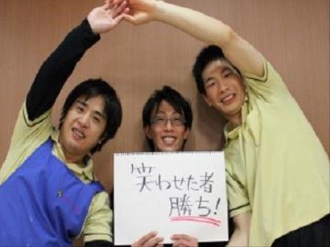「笑わせた者勝ち！」と書かれた用紙を真ん中にポーズを取る男性三名