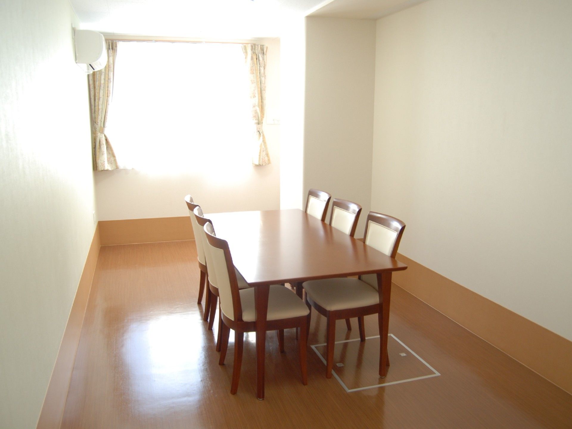 部屋の中央に、６人掛けのダイニングテーブルが置かれている。エアコンが備わっているので、季節を問わず快適に過ごすことができる。