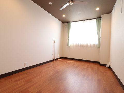 シーリングファンが天井には設置されており、緑のカーテンのついた大きな窓からは屋内に光が差し込んでいます。