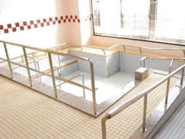 周辺に手すりがたくさん設置されている、お湯が張られていない大きな浴槽