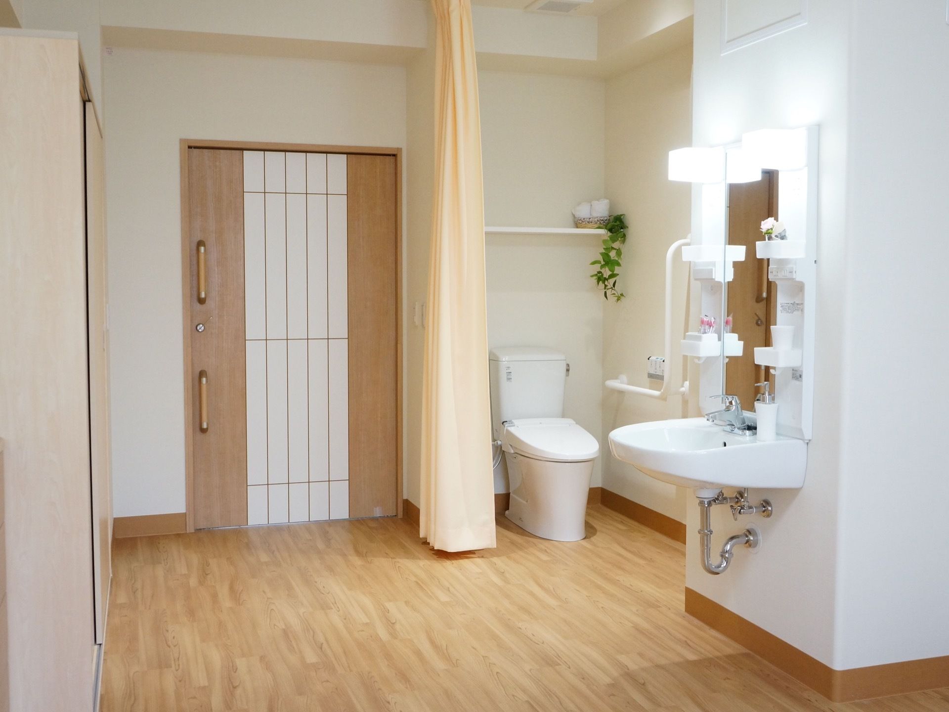 居室のトイレはカーテンで仕切られている。また、洗面台の蛇口はシングルレバー式で操作しやすいものになっている。