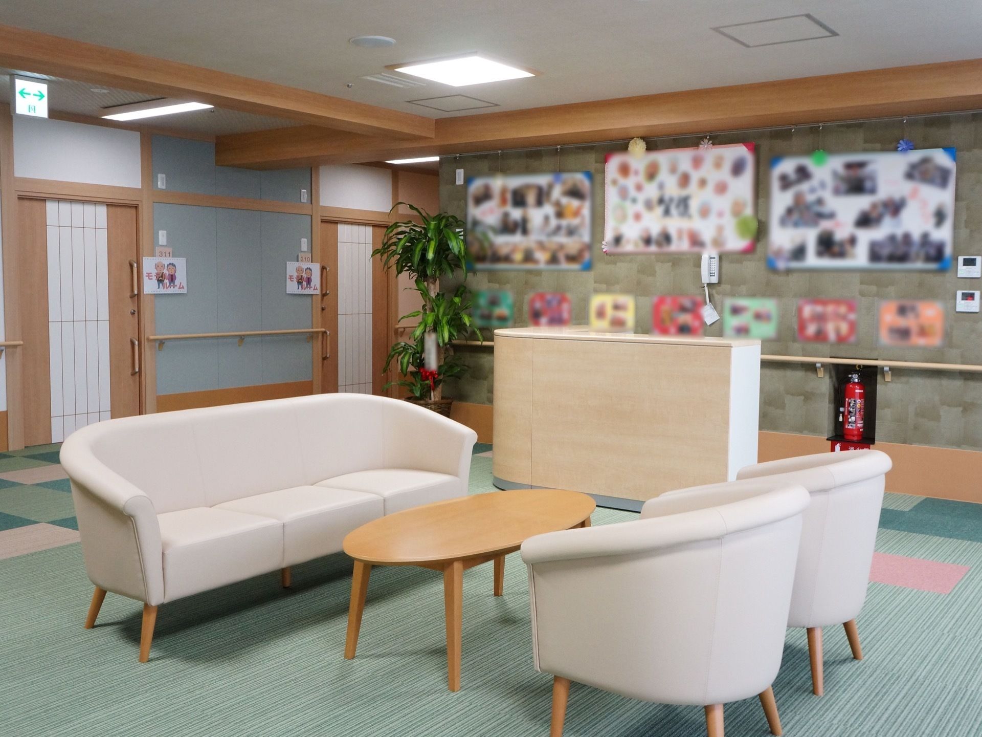 館内の中央にソファとテーブルが置かれている。また、壁には入居者様の写真が貼られたボードが飾られている。