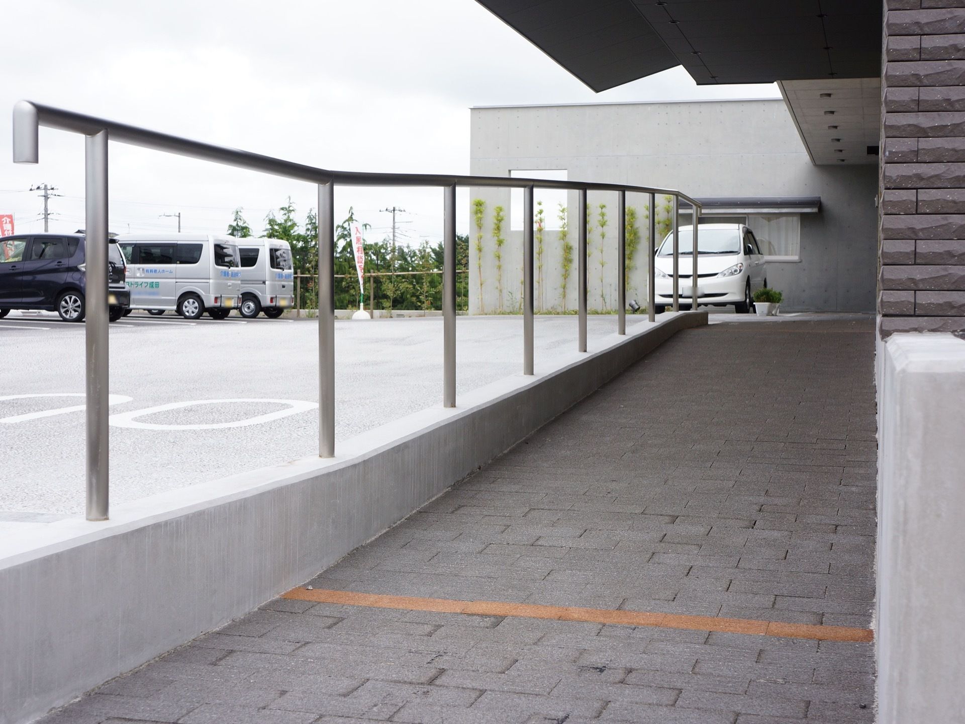 入口の脇にあるスロープ。片側に手すりが取り付けられている。施設の目の前には駐車スペースが設けられている。