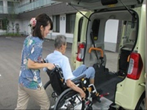 スタッフに押されながら、車椅子でスロープを使って車に乗り込む入居者