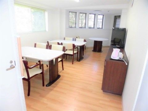 右手に設置されたこげ茶色のタンスの上に、テレビや電気ポットが置かれているダイニング