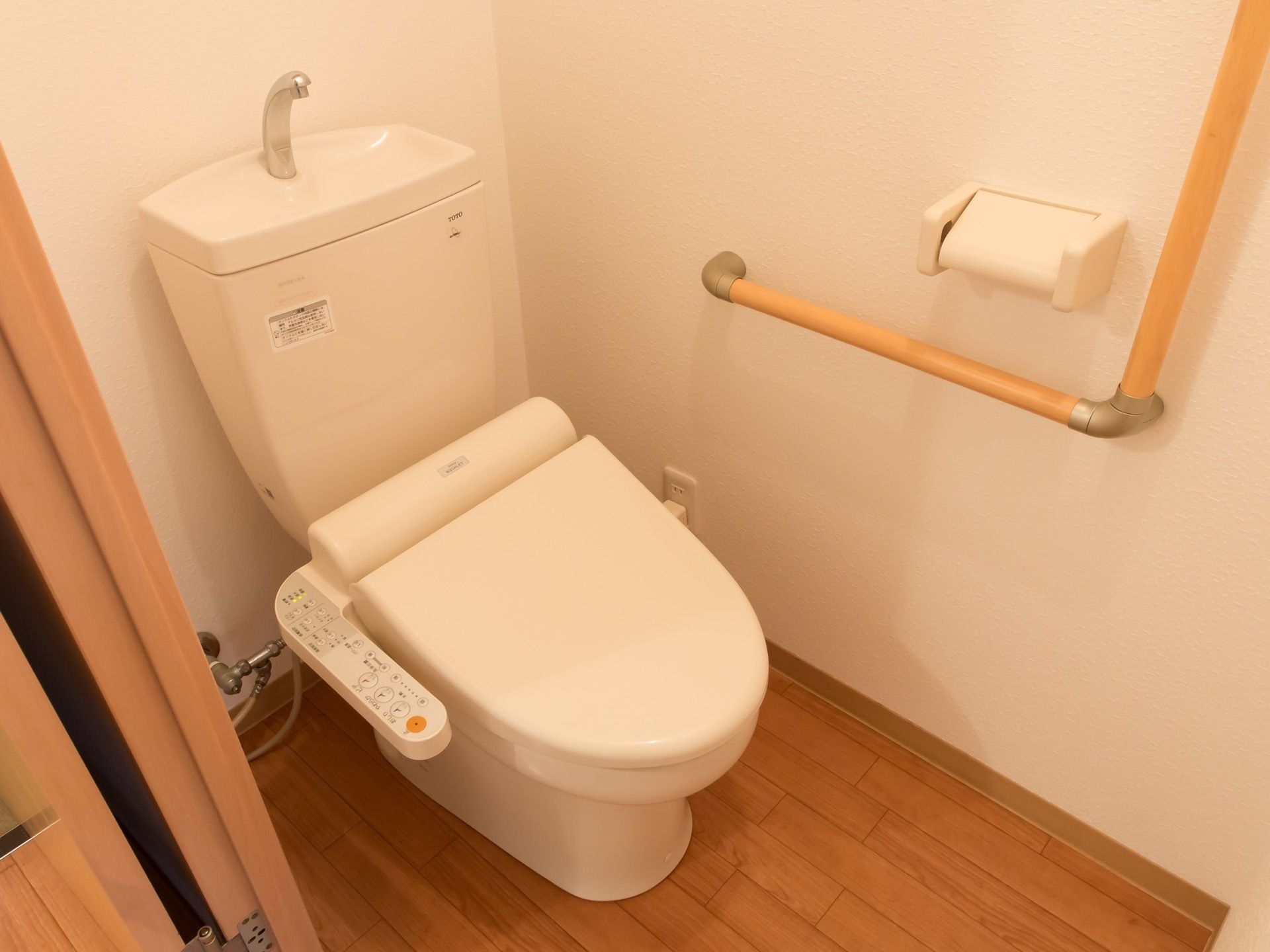 トイレは暖房洗浄機能つきの便座になっている。トイレットペーパーホルダーを取り巻くように手すりが設置されている。