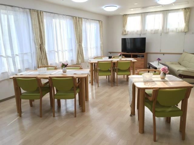 テーブル上に敷かれたクロスの上に、花が飾られているテーブルセットが複数設置されているリビング