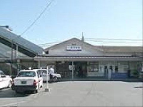 最寄りの駅は、三角屋根の中央に駅名が表示されている。駅前は、コンクリート舗装の広いスペースがあり、客待ちのタクシーが数台停車している。