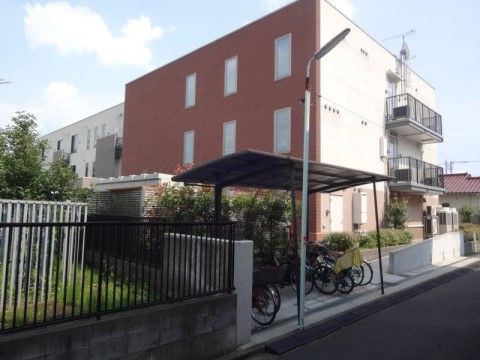屋根付きの駐輪場があり、その向こう側に施設が建っている風景