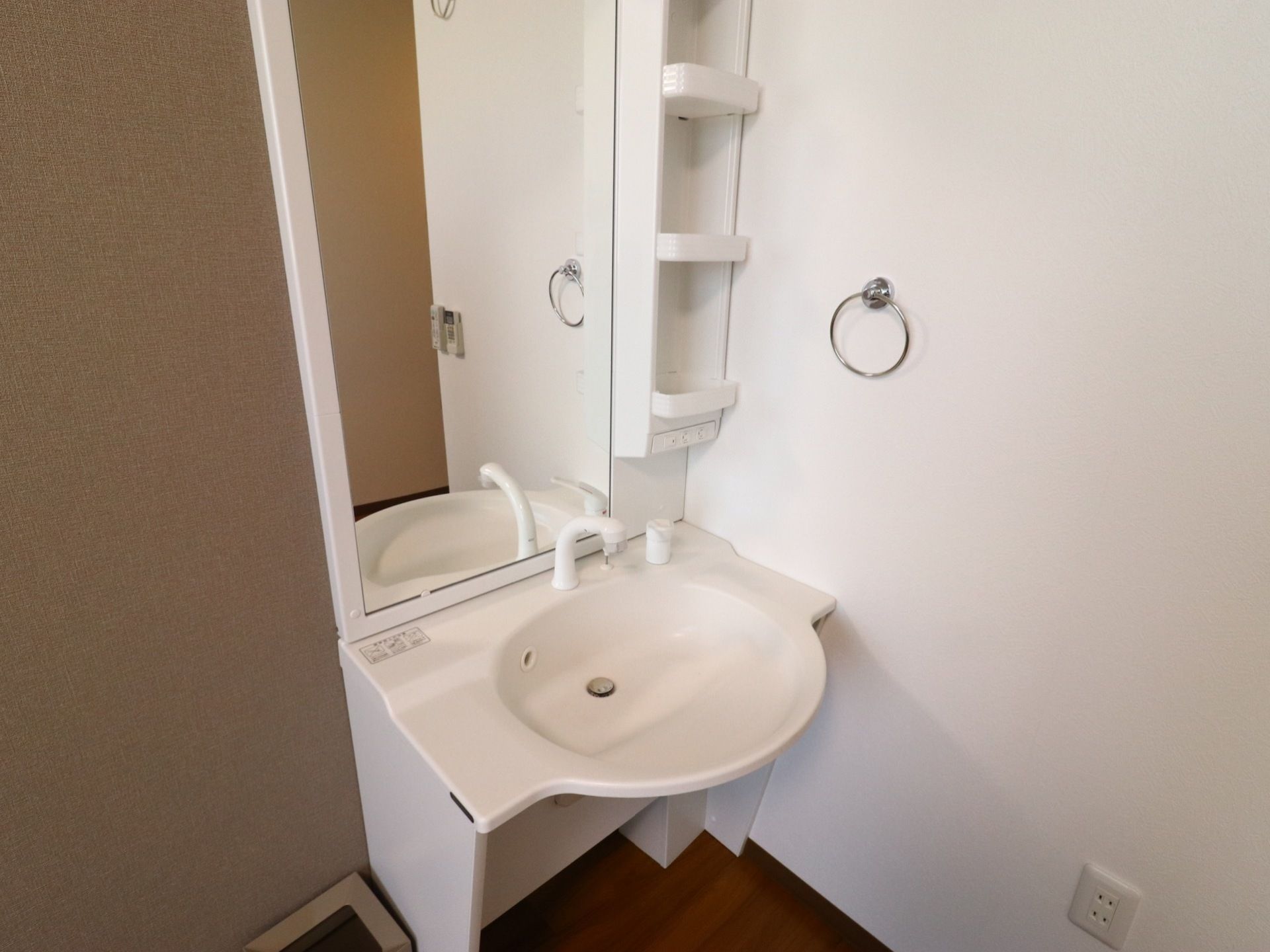 部屋には白い洗面台が設けられている。車椅子でも利用できるように下が空いていおり、大きな鏡と収納できる棚がある。