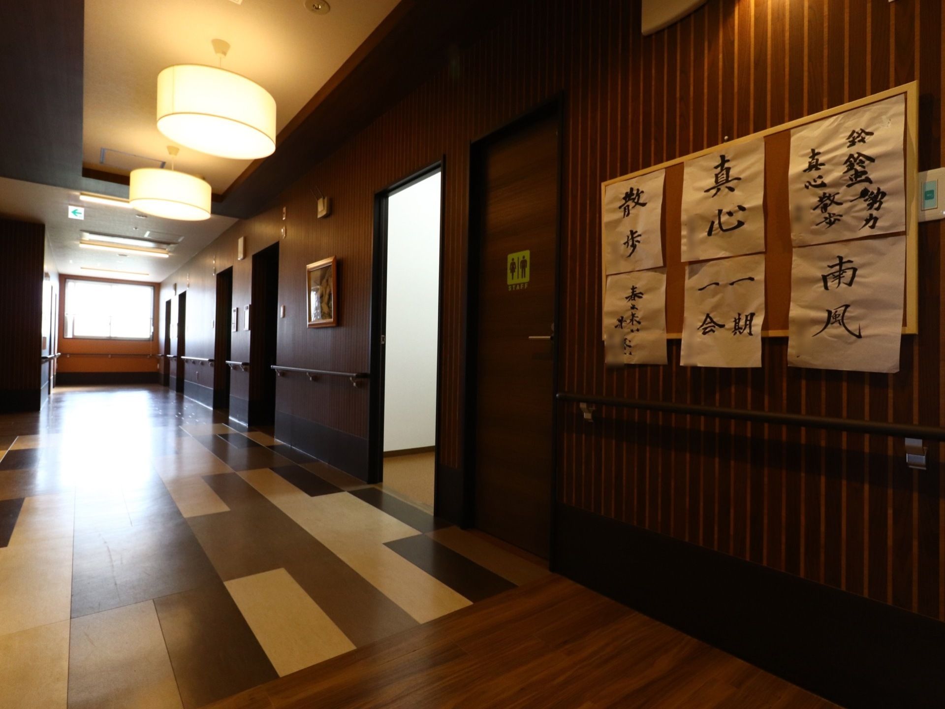 和風仕立ての落ち着いた廊下の壁には、入居者様の書道作品が飾られている。さりげなく共同のトイレも設けられている。