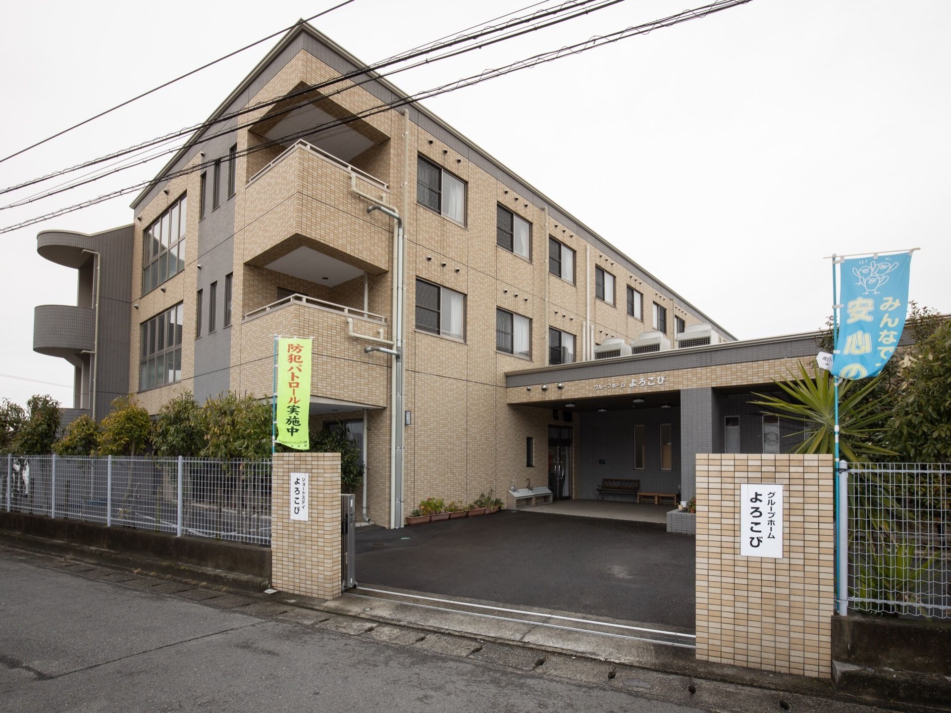 施設の外壁はレンガ造りで、2階と3階には居室が並んでいる。玄関には、屋根の下に広いスペースが設けられている。