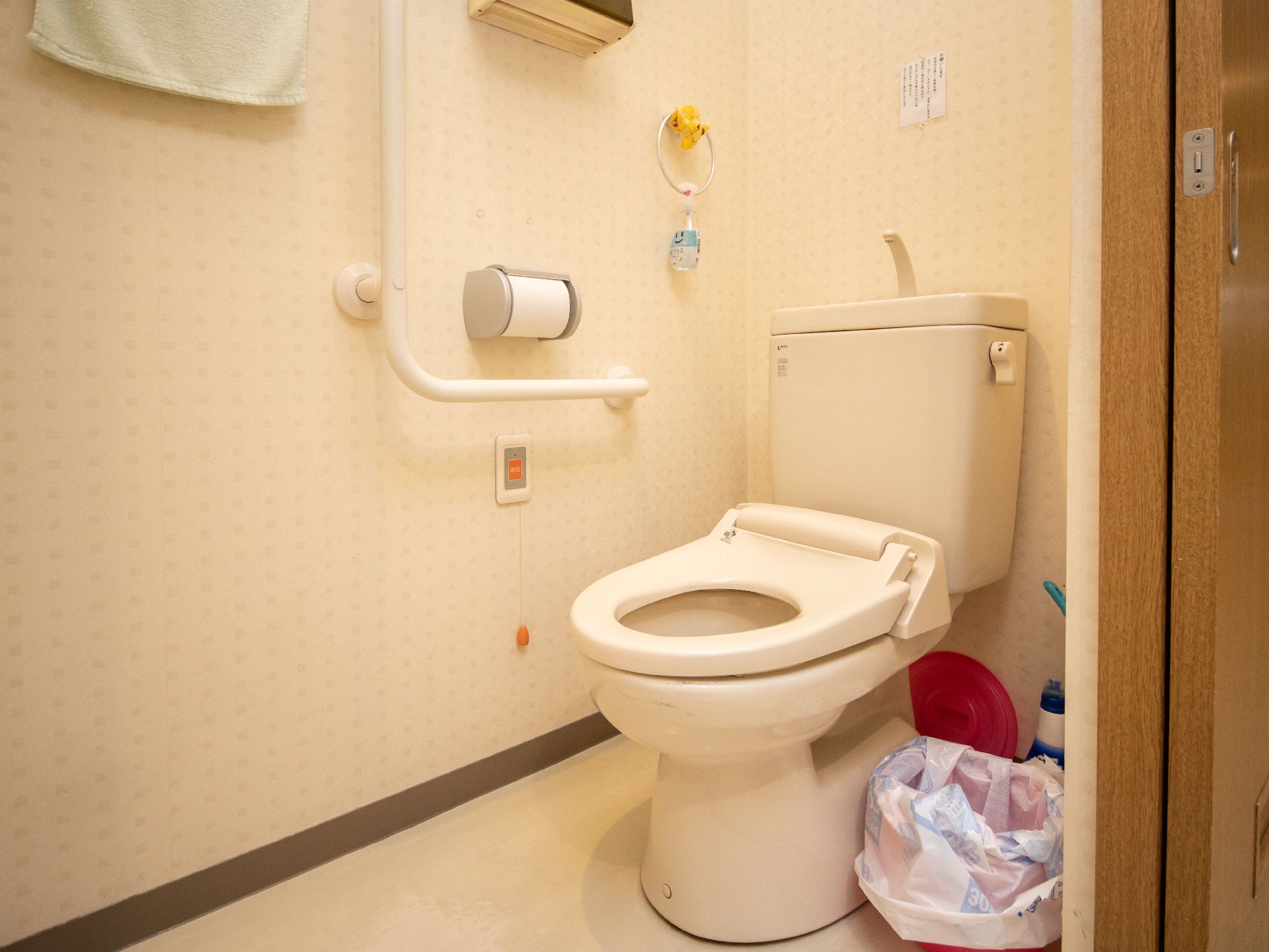 洋式便器の横にL字型の手すりや消毒液が設置されているトイレ個室