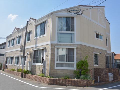 えんじの瓦屋根に白い窓枠の窓が並ぶ、洋風な建物。周囲には花壇が設けられ、様々な植物が植えられている。