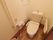洋式トイレがある。壁には職員を呼ぶナースコールのボタンが設置されている。ペーパーロールが2つ備え付けられている。