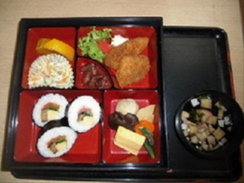 五か所に仕切られた赤いトレーに、太巻きやおかずが盛り付けられたお膳
